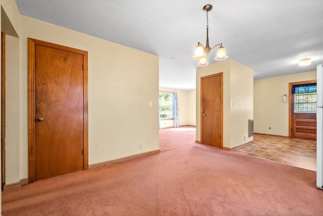 unfurnished room featuring a notable chandelier, light carpet, and heating unit