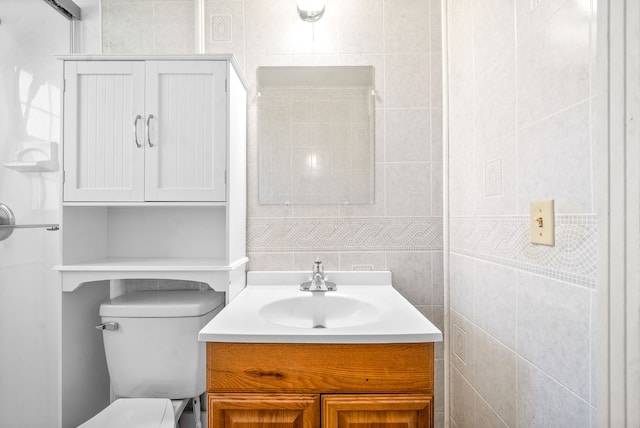 bathroom with tile walls, vanity, and toilet