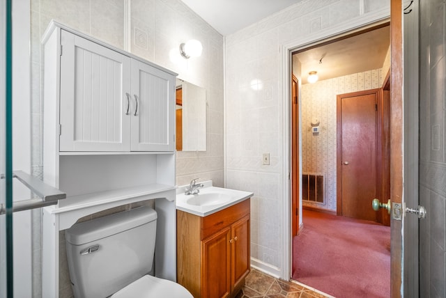 bathroom featuring vanity, toilet, and tile walls