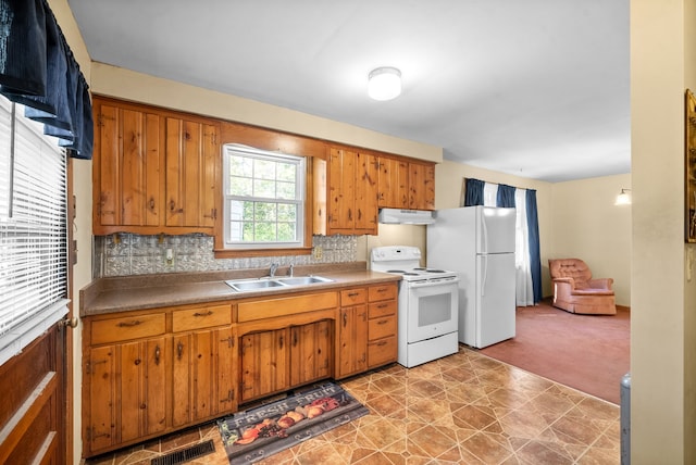 kitchen with sink, light colored carpet, white appliances, and tasteful backsplash