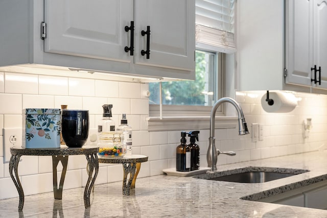 kitchen featuring sink, light stone countertops, decorative backsplash, and white cabinets