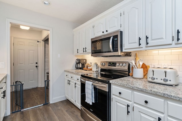 kitchen with decorative backsplash, white cabinets, dark hardwood / wood-style flooring, a textured ceiling, and stainless steel appliances