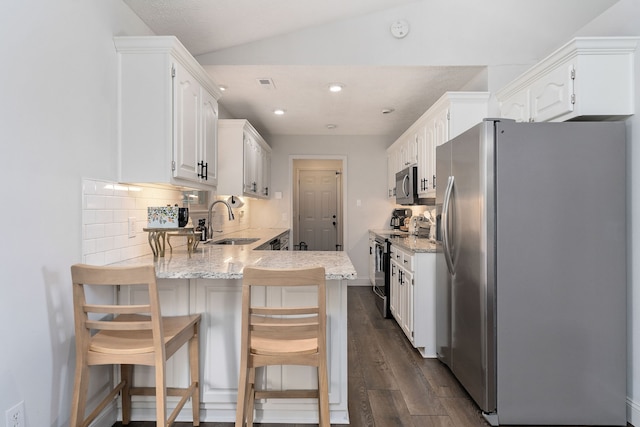 kitchen featuring a breakfast bar area, dark wood-type flooring, stainless steel appliances, sink, and white cabinets