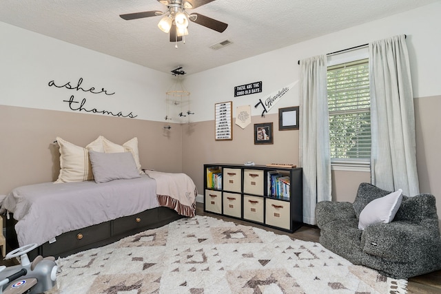 bedroom with hardwood / wood-style floors, a textured ceiling, and ceiling fan