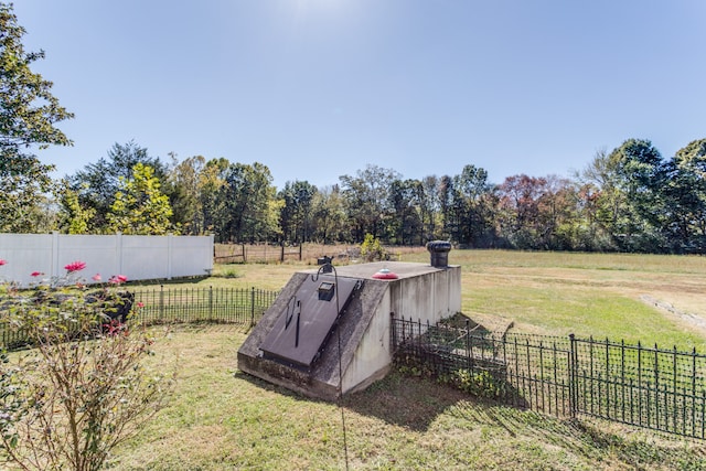 entry to storm shelter featuring a lawn and a rural view