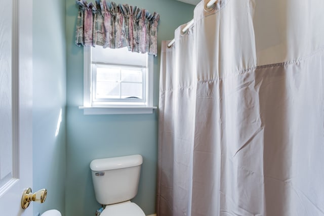 bathroom featuring a shower with curtain and toilet