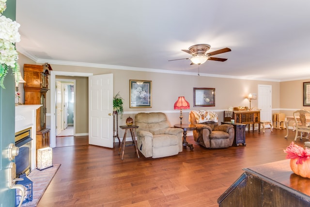 living room with a brick fireplace, ornamental molding, ceiling fan, and dark hardwood / wood-style flooring