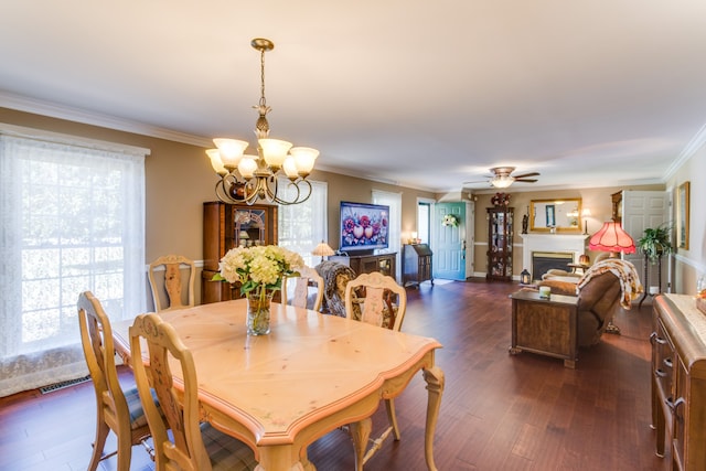 dining space with ornamental molding, dark wood-type flooring, and ceiling fan with notable chandelier