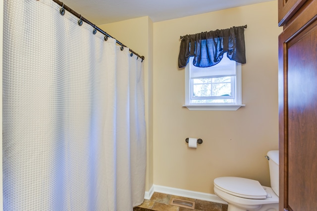 bathroom with a shower with shower curtain and toilet