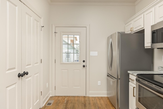 kitchen featuring light hardwood / wood-style floors, white cabinets, stainless steel appliances, and ornamental molding