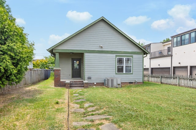 rear view of house with central air condition unit, a yard, and a balcony