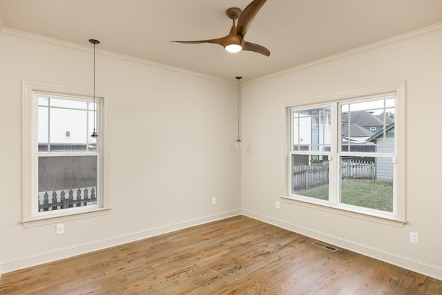 spare room featuring crown molding, wood-type flooring, and a healthy amount of sunlight