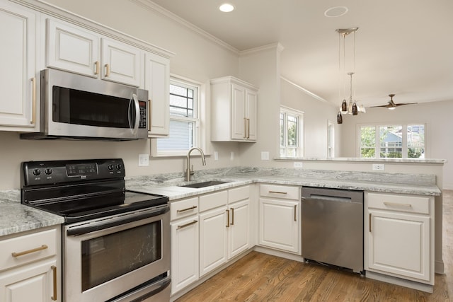 kitchen featuring stainless steel appliances, ornamental molding, sink, white cabinets, and light hardwood / wood-style floors