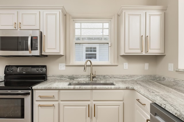 kitchen featuring light stone countertops, sink, white cabinetry, and stainless steel appliances