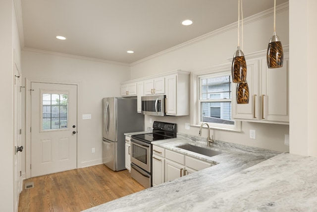 kitchen with white cabinets, appliances with stainless steel finishes, light stone countertops, light hardwood / wood-style floors, and sink