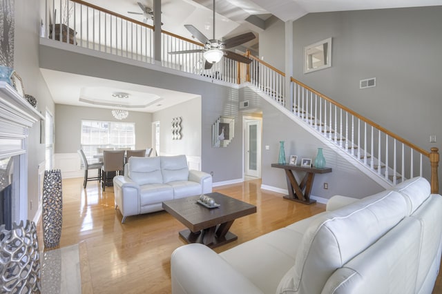 living room featuring light hardwood / wood-style flooring, high vaulted ceiling, and ceiling fan with notable chandelier