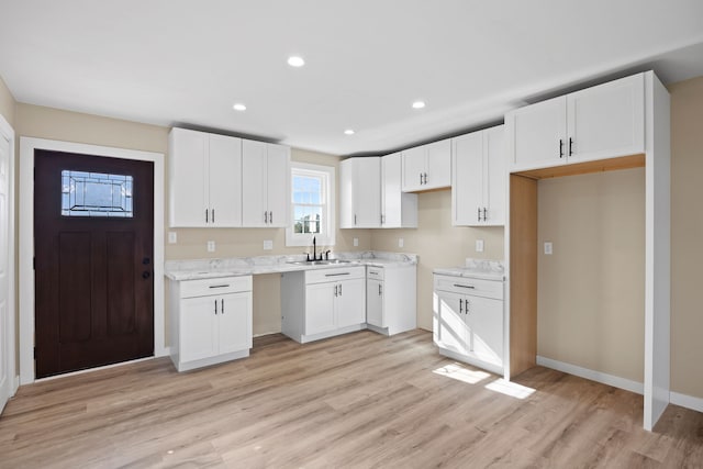 kitchen featuring white cabinetry, sink, and light wood-type flooring