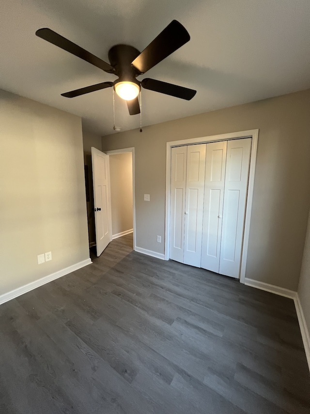 unfurnished bedroom with dark wood-type flooring, ceiling fan, and a closet