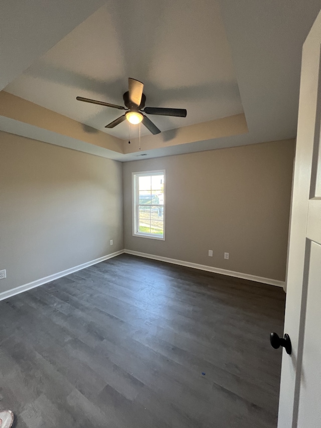 spare room featuring ceiling fan, a raised ceiling, and dark hardwood / wood-style floors