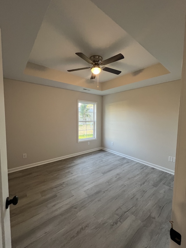 spare room with ceiling fan, a raised ceiling, and hardwood / wood-style floors