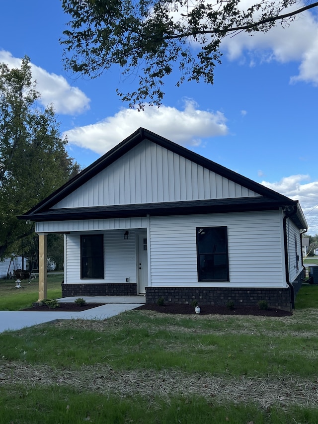 view of front of property featuring a front yard, covered porch, and central AC unit