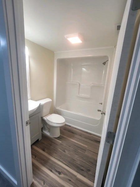 full bathroom featuring vanity, toilet, wood-type flooring, and  shower combination