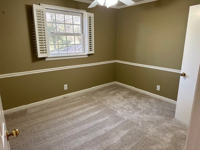 carpeted empty room featuring ornamental molding and ceiling fan