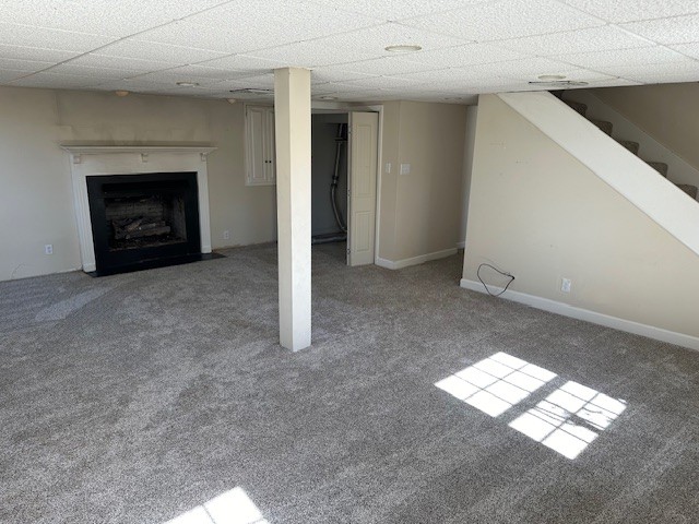 basement with a drop ceiling and light colored carpet