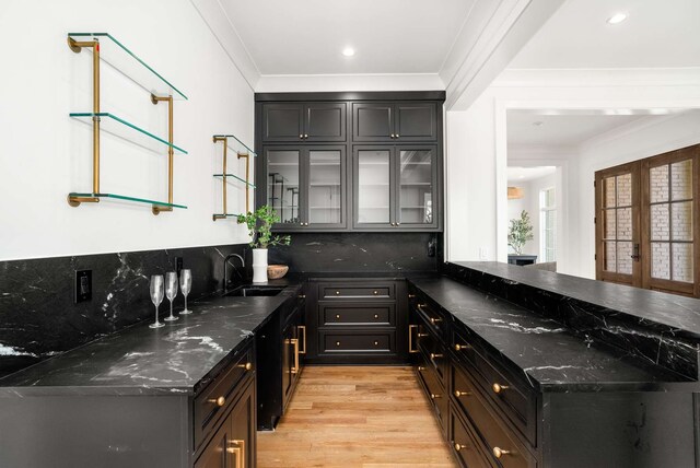 bar with french doors, sink, light hardwood / wood-style flooring, dark stone countertops, and tasteful backsplash