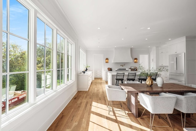 dining room with a wealth of natural light, light hardwood / wood-style floors, and ornamental molding