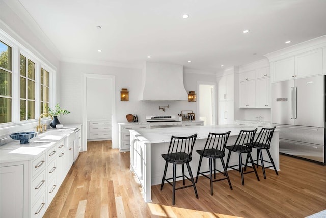 kitchen featuring white cabinets, plenty of natural light, built in fridge, and custom exhaust hood