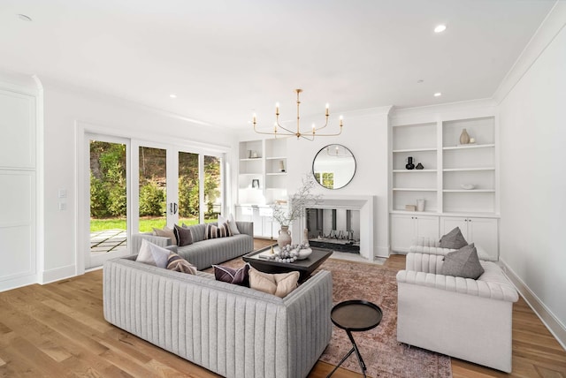 living room with french doors, light wood-type flooring, crown molding, and a chandelier