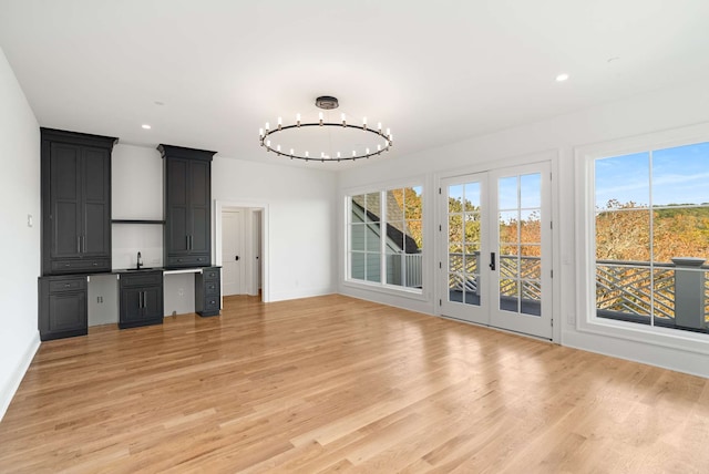 unfurnished living room with light hardwood / wood-style floors, sink, and a chandelier