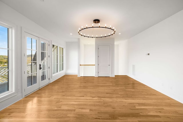 spare room featuring a chandelier and light hardwood / wood-style floors