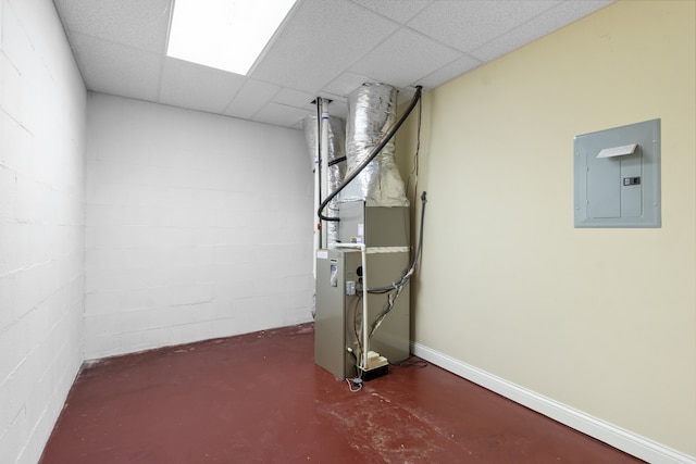 basement featuring a drop ceiling, electric panel, and heating unit