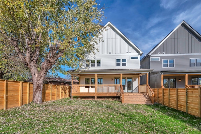 back of property with a lawn and a wooden deck