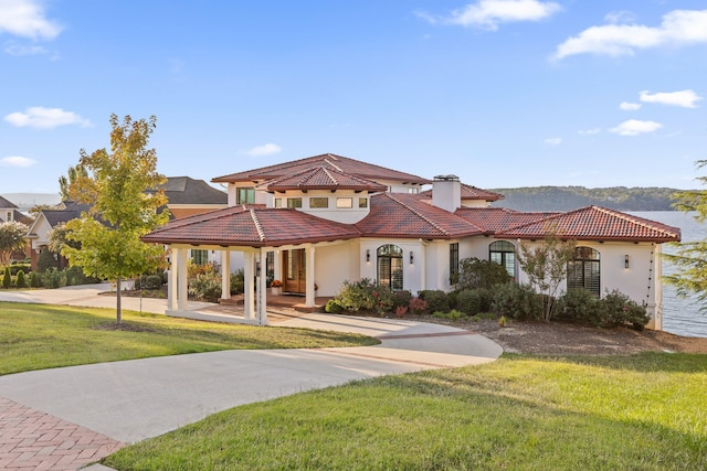 mediterranean / spanish home with a water view and a front lawn