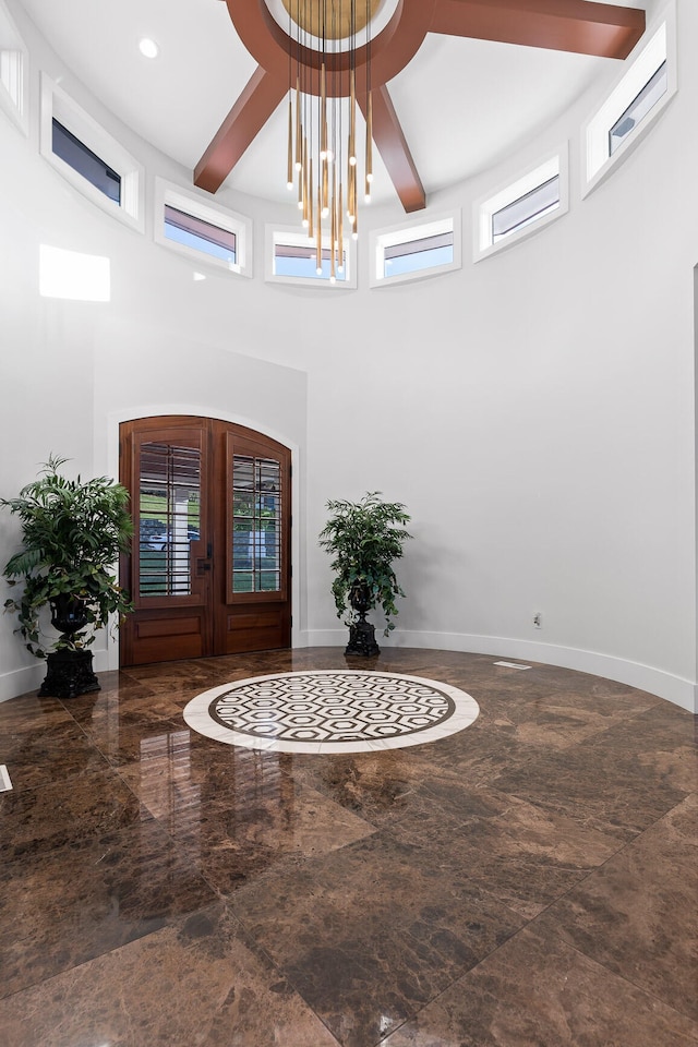 entryway with a towering ceiling, beamed ceiling, french doors, and an inviting chandelier