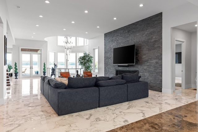 living room featuring french doors, a notable chandelier, and a fireplace