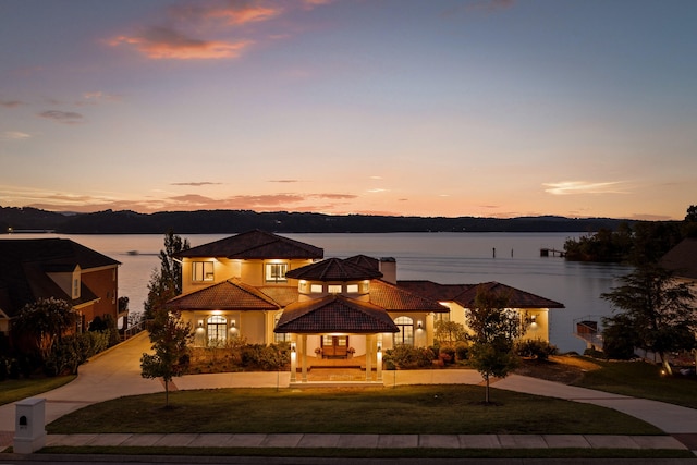 view of front of house featuring a water and mountain view and a lawn