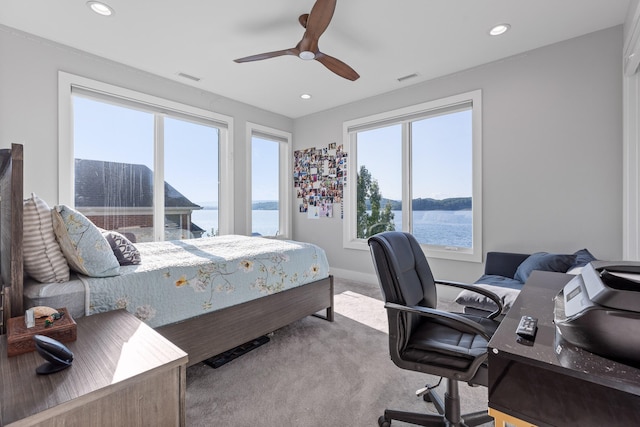 carpeted bedroom featuring a water view and ceiling fan