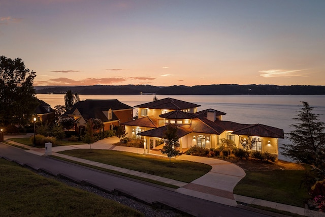 view of front of property with a water view and a lawn