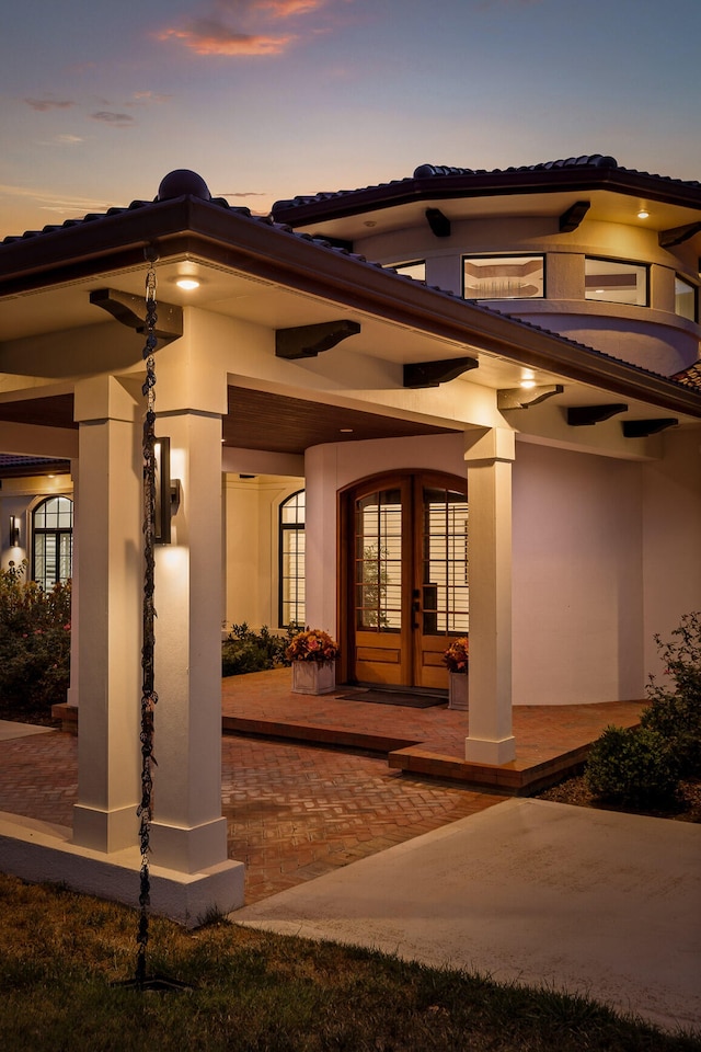 exterior entry at dusk featuring a patio and french doors