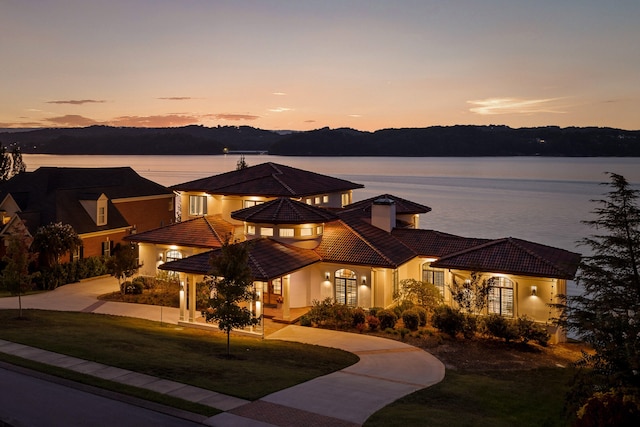 view of front facade featuring a lawn and a water view