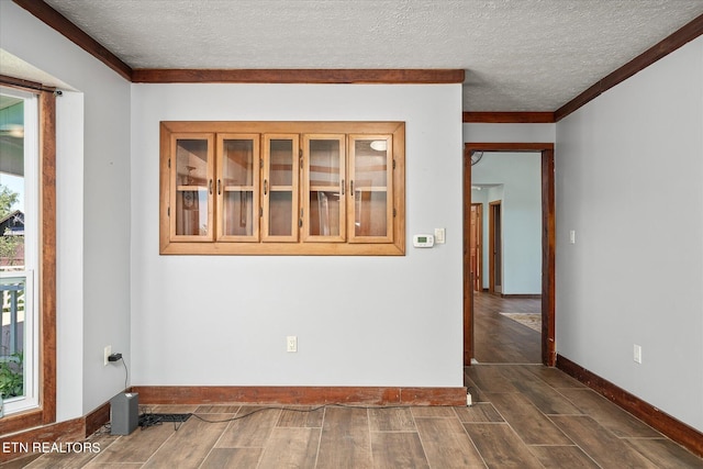 unfurnished room featuring a textured ceiling, ornamental molding, and dark hardwood / wood-style floors