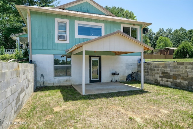 back of property with board and batten siding, a patio, metal roof, a lawn, and a fenced backyard