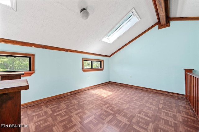 bonus room with a textured ceiling, vaulted ceiling with skylight, and baseboards