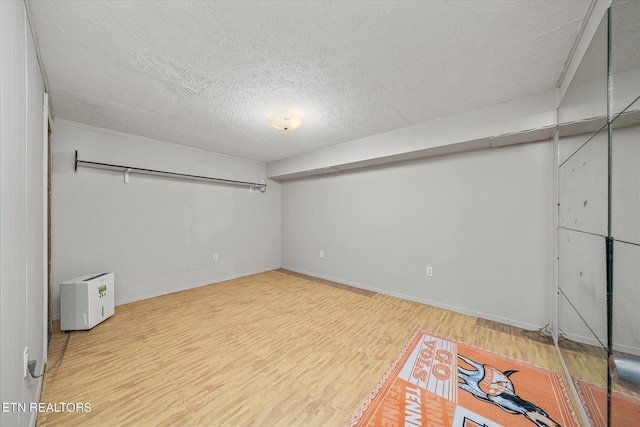 finished below grade area featuring baseboards, wood finished floors, and a textured ceiling