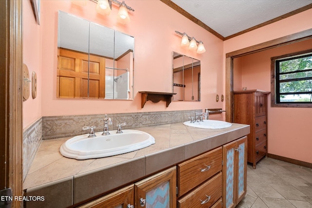 bathroom with vanity, crown molding, a textured ceiling, and tile patterned flooring