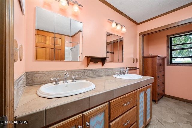 full bath with tile patterned floors, ornamental molding, double vanity, and a sink